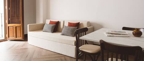 A living room with a sofa, two pillows, a table, and a chair.