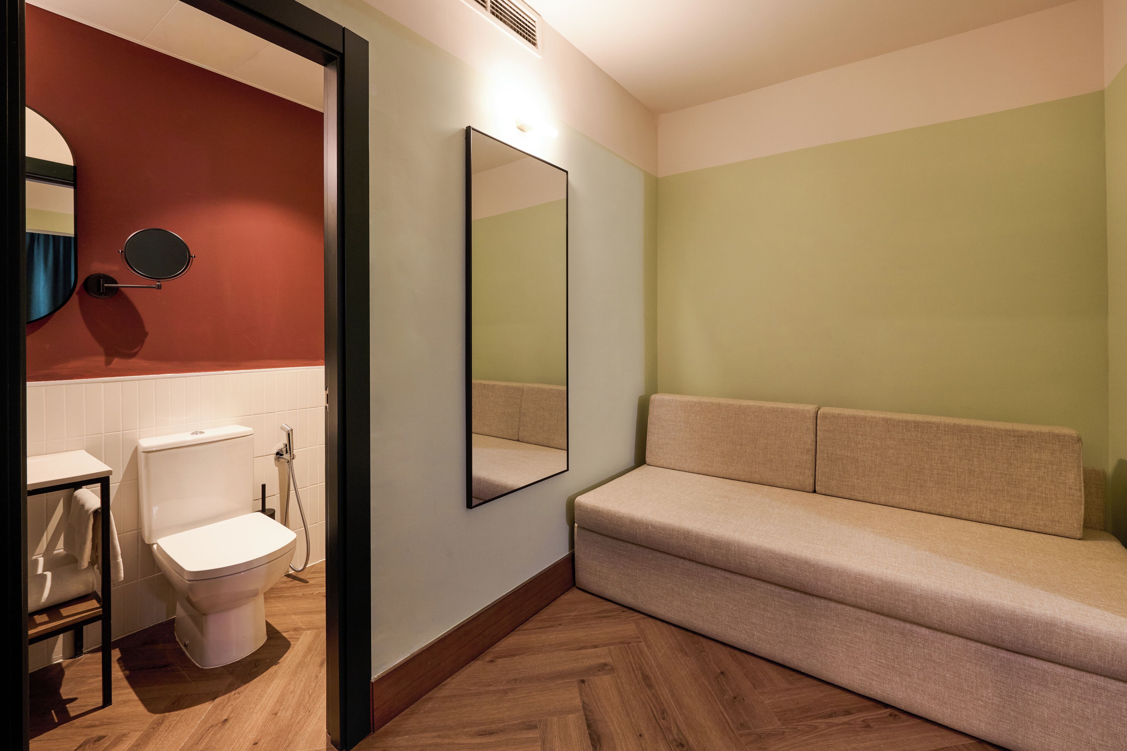 Un bagno con il water, un lavandino, uno specchio e un divano.