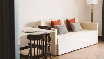 A modern living room with a white sofa, a dining table, and a lamp.