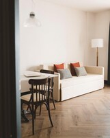 Un salon moderne avec un canapé blanc, une table à manger et une lampe.