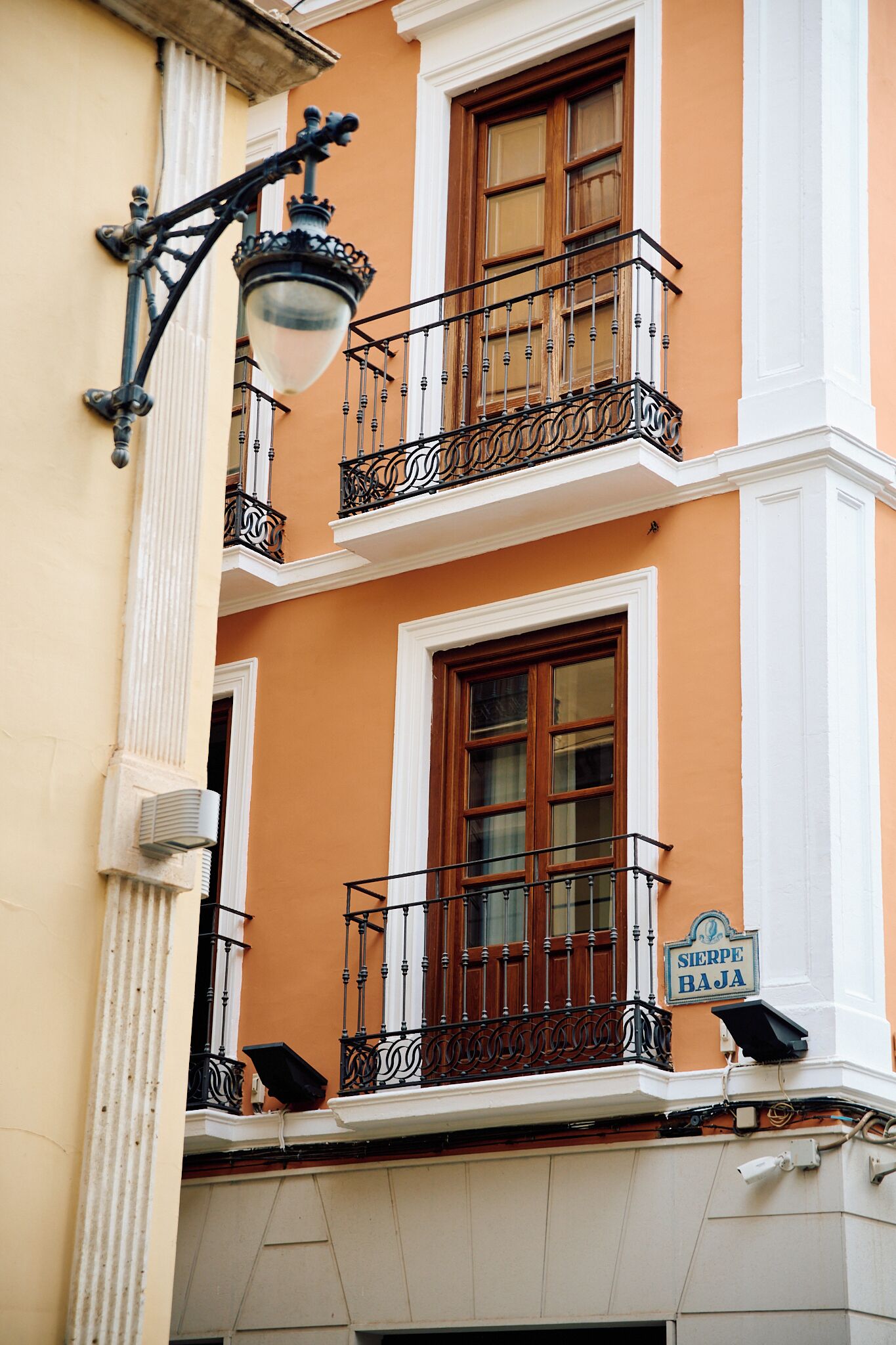 A building with a balcony, a street lamp, and a sign reading "Sierpe Baja".