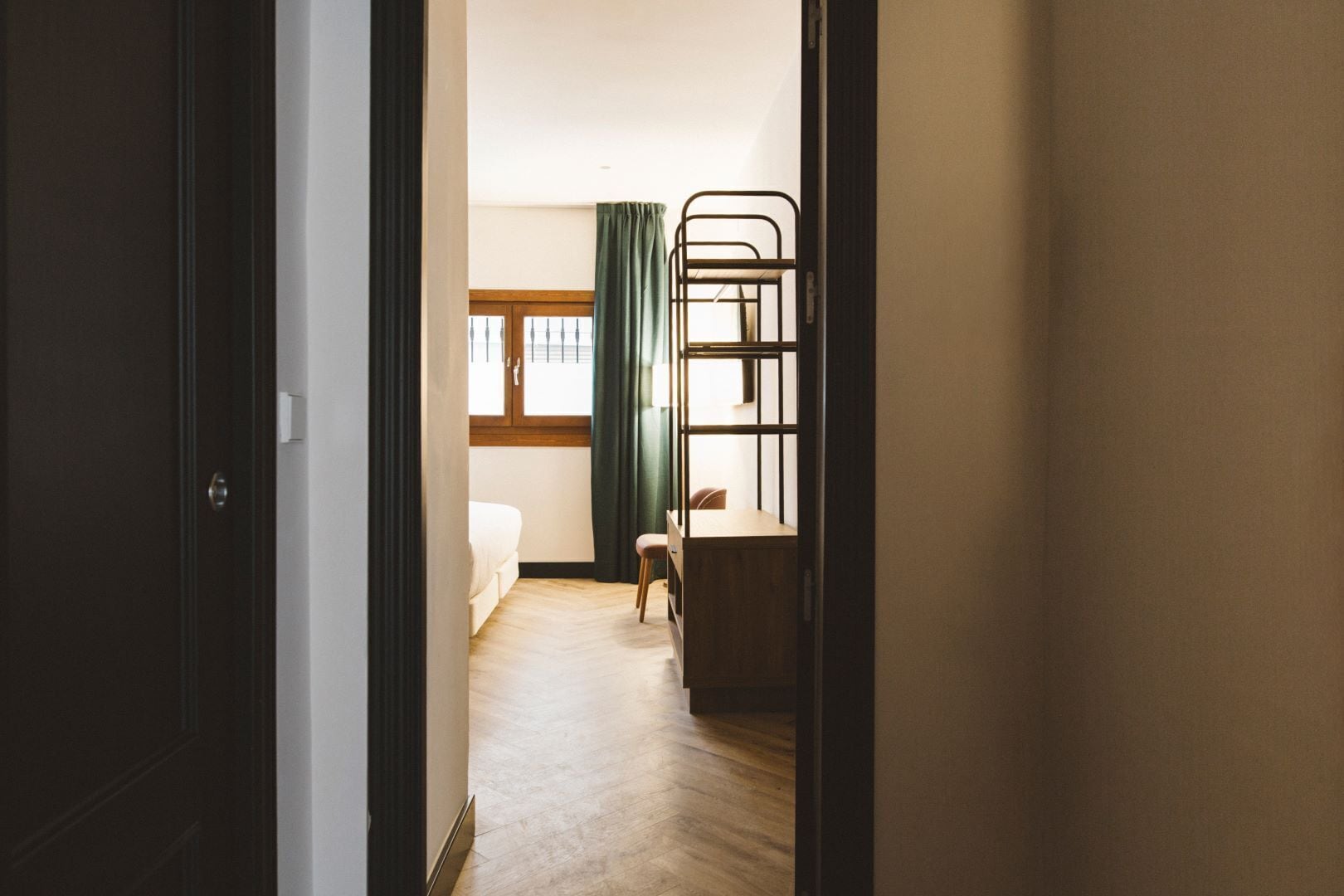 Una habitación con literas, un escritorio, una silla y una ventana con cortinas.