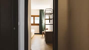 Una habitación con literas, un escritorio, una silla y una ventana con cortinas.