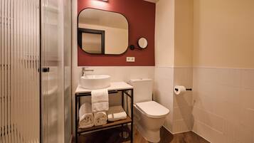 A bathroom with a sink, toilet, and a mirror.