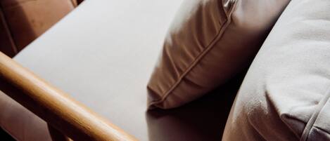 A wooden chair with a white cushion and a matching pillow.