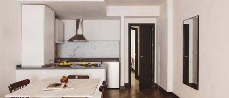 A modern kitchen with white cabinetry, a marble countertop, and a dining area with a white table and wooden chairs.