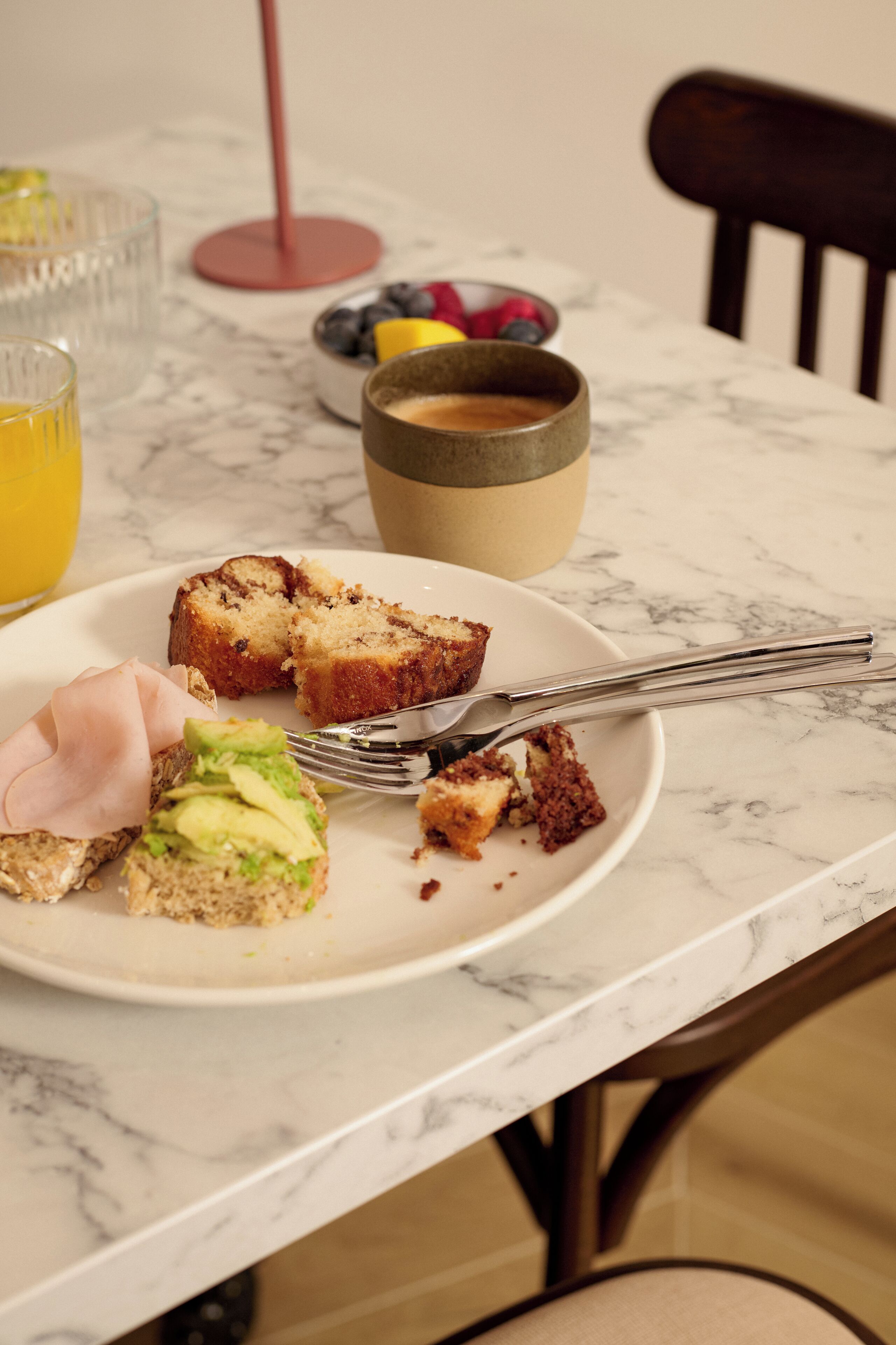Una escena de desayuno con un plato de comida, una taza y un vaso de jugo de naranja sobre una mesa de mármol.