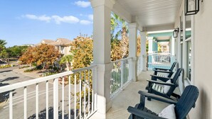 Ein Balkon mit weißen Geländern, Blick auf die Straße und eine Reihe blauer Stühle.