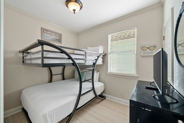 A bunk bed room with a television and a wall clock. - Recently Refreshed Crystal Beach Retreat Pet Friendly, Steps to Pool, Shuttle & Emerald Coast! (Destin)