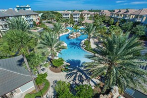 A resort with a central swimming pool, palm trees, and multiple buildings with balconies. - Recently Refreshed Crystal Beach Retreat Pet Friendly, Steps to Pool, Shuttle & Emerald Coast! (Destin)
