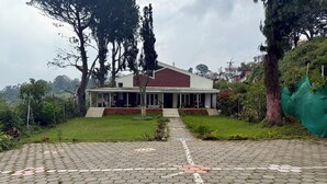 A house with a red roof and a porch. - Nilgiris Inn (Kotagiri)