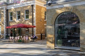 An outdoor seating area with tables and chairs in front of The Chelsea Grocer. - Sloane Gardens VIII by onefinestay (London)