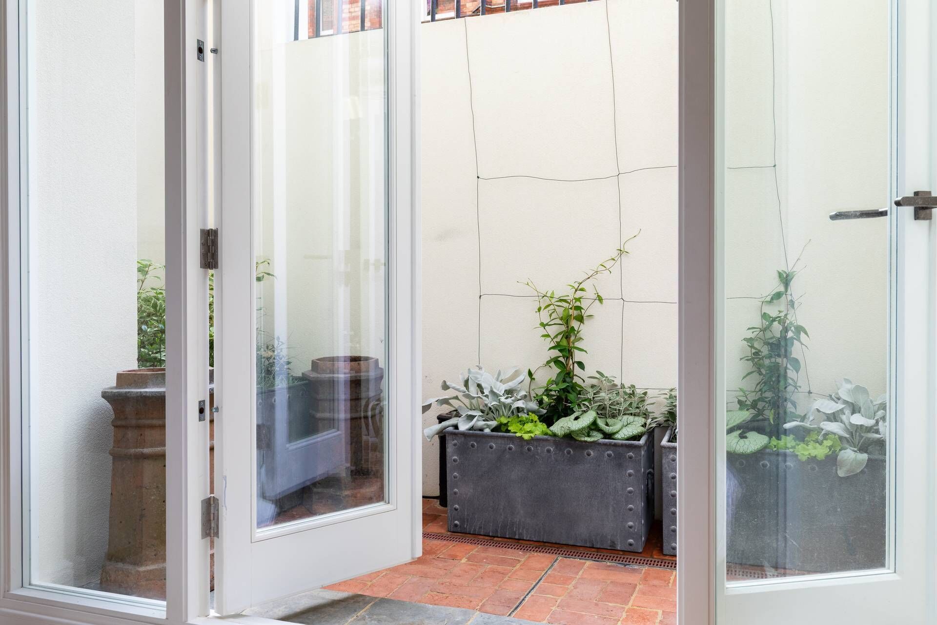 A glass door leading to a patio area with potted plants and a tiled floor.