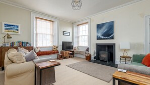 A living room with a sofa, a coffee table, a fireplace, a television, and a bookshelf. - Toll Green View | Elie (Elie)