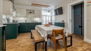 A modern kitchen with green cabinets, a wooden dining table, and a bench. - Toll Green View | Elie (Elie)