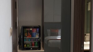 A compact room with a bed, a small kitchenette, and a vending machine. - Happiness Hotel (Ulaanbaatar)
