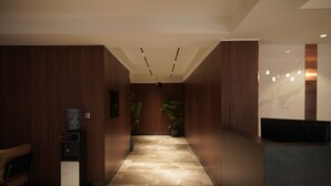 A modern hallway with wooden paneling, a water dispenser, and potted plants. - Happiness Hotel (Ulaanbaatar)