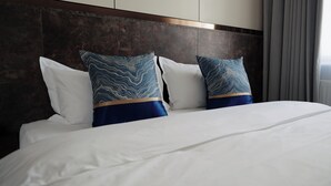 A hotel room with a large bed, two patterned pillows, and a dark headboard. - Happiness Hotel (Ulaanbaatar)