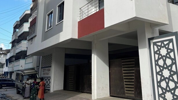 A multi-story building with balconies, a covered entrance, and a sign indicating it is a city view apartment. - 3BR High-Rise Apartment • Prime Location 12th floor (Mombasa)