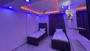 A modern bedroom with two beds, a ceiling fan, and ambient lighting. - 3BR High-Rise Apartment • Prime Location 12th floor (Mombasa)