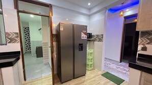 A modern kitchen with two stainless steel refrigerators, a wooden door, and a herringbone patterned backsplash. - 3BR High-Rise Apartment • Prime Location 12th floor (Mombasa)