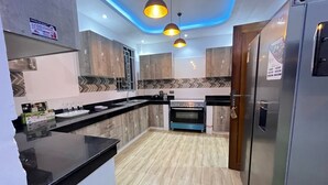 Una cucina moderna con mobili in legno, un piano di lavoro nero, un forno integrato e luci a sospensione.