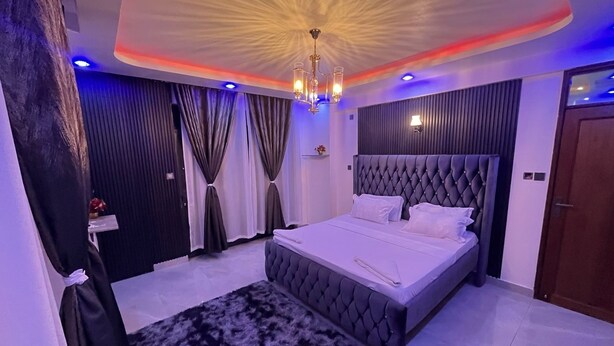 A modern bedroom with a tufted headboard, a large bed, and a fluffy rug. - 3BR High-Rise Apartment • Prime Location 12th floor (Mombasa)