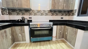 A compact kitchen with a built-in oven, a coffee maker, and a microwave on the countertop. - 3BR High-Rise Apartment • Prime Location 12th floor (Mombasa)