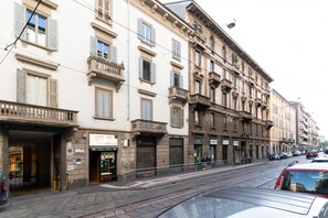 A street with buildings, a restaurant named 'Lucky Charlie,' and a closed shop with a shutter. - GuestHost - Modern Apartment Near Darsena (Milan)