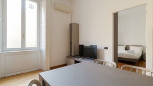 Une pièce minimaliste comprenant un lit, une télévision, un bureau et une fenêtre.