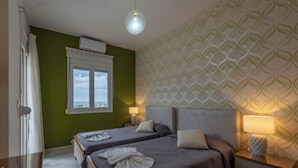 Ein Hotelzimmer mit zwei Betten, einem Fenster mit Blick, einer Wand mit Muster und einer Deckenleuchte.