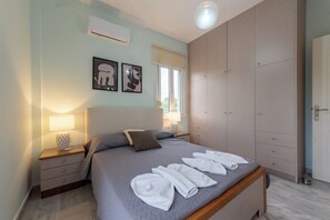 A bedroom with a bed, bedside tables, a wardrobe, and artwork on the wall. - Villa Pantelis With Private Pool (Rethymno)
