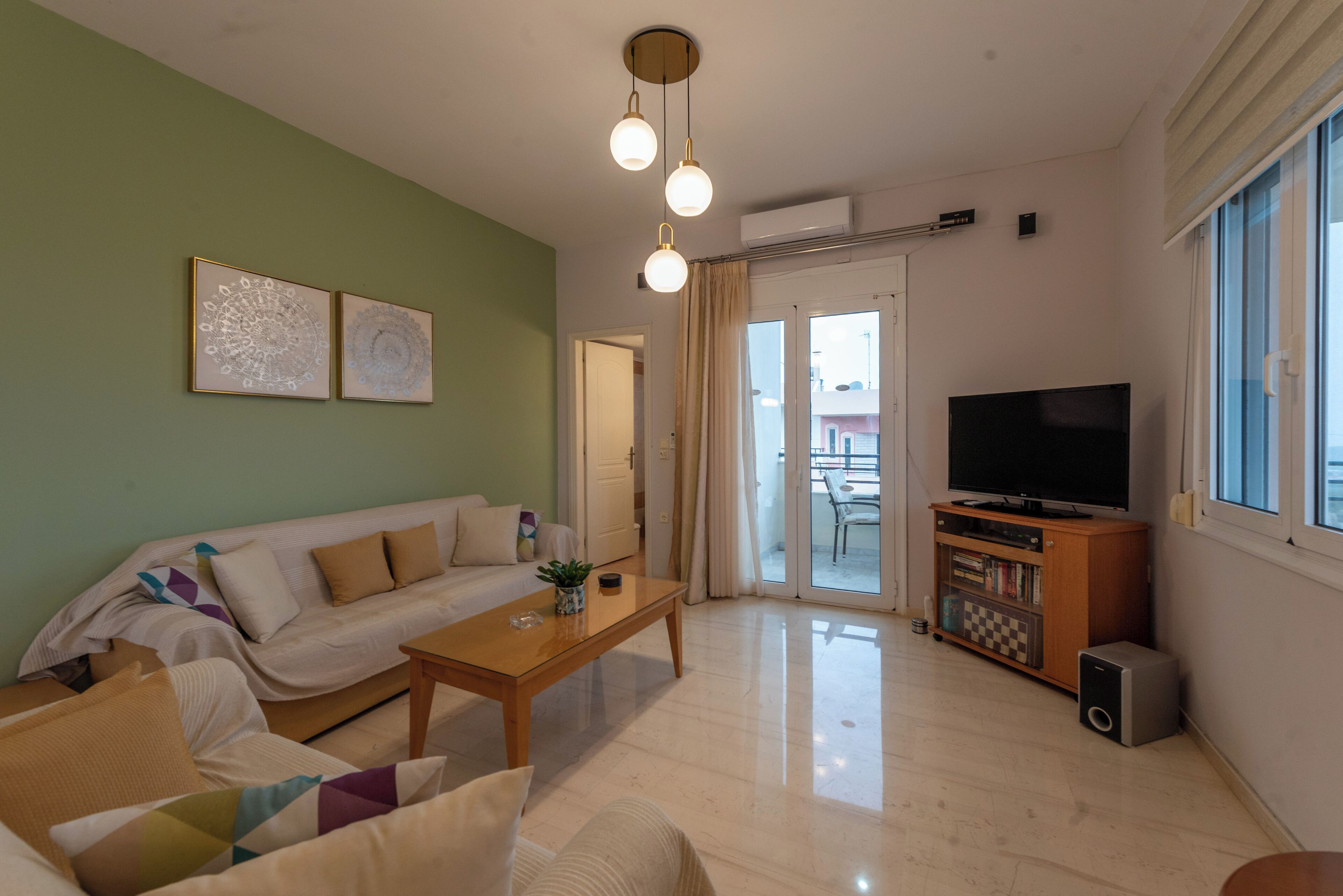 A living room with a sofa, coffee table, and a TV stand with a flat-screen TV and speakers.
