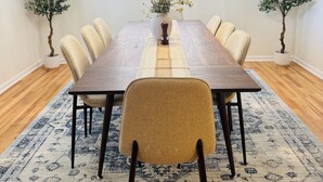 A dining room with a long wooden table, beige chairs, a patterned rug, and two potted plants. - 5/3 Pool Home In Central Lakeland, Pet Friendly! (Lakeland)