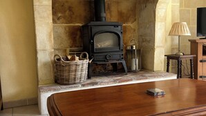 Uma sala de estar aconchegante com lareira de pedra, uma mesa de madeira e uma cesta de vime.