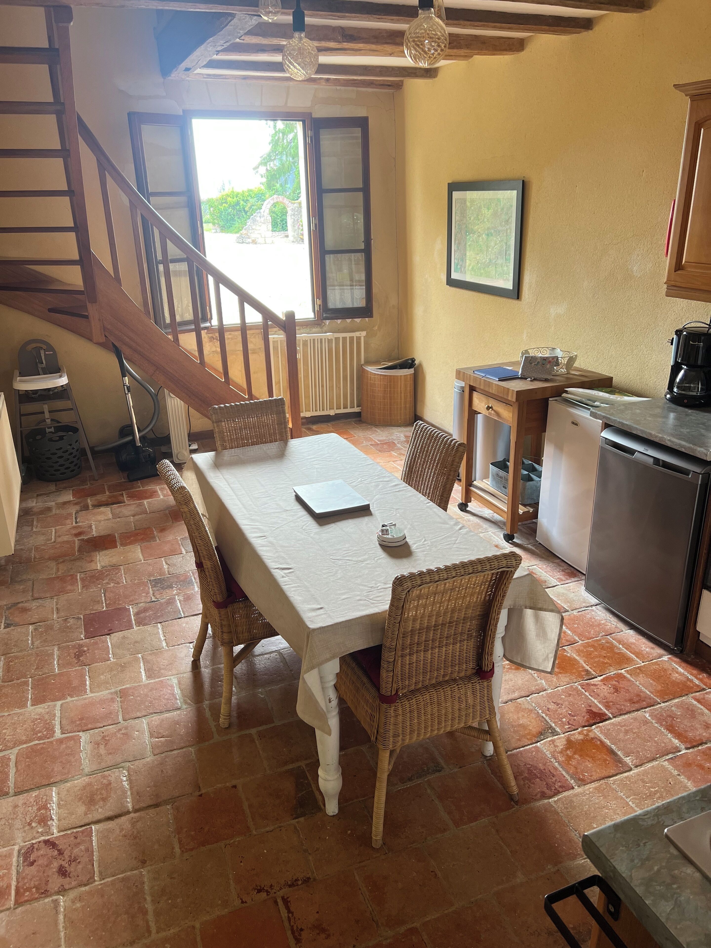 A kitchen with a dining area, a staircase, and a view of the outdoors.