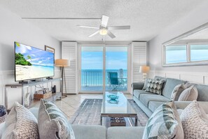 A living room with a television, sofa, coffee table, and a balcony with a view. - Sand Castle II - #2601 and #2602 (Indian Shores)