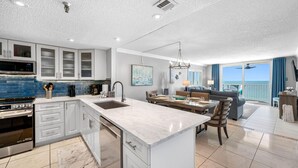 Una cocina moderna con una isla central, electrodomésticos integrados y un comedor con vistas.