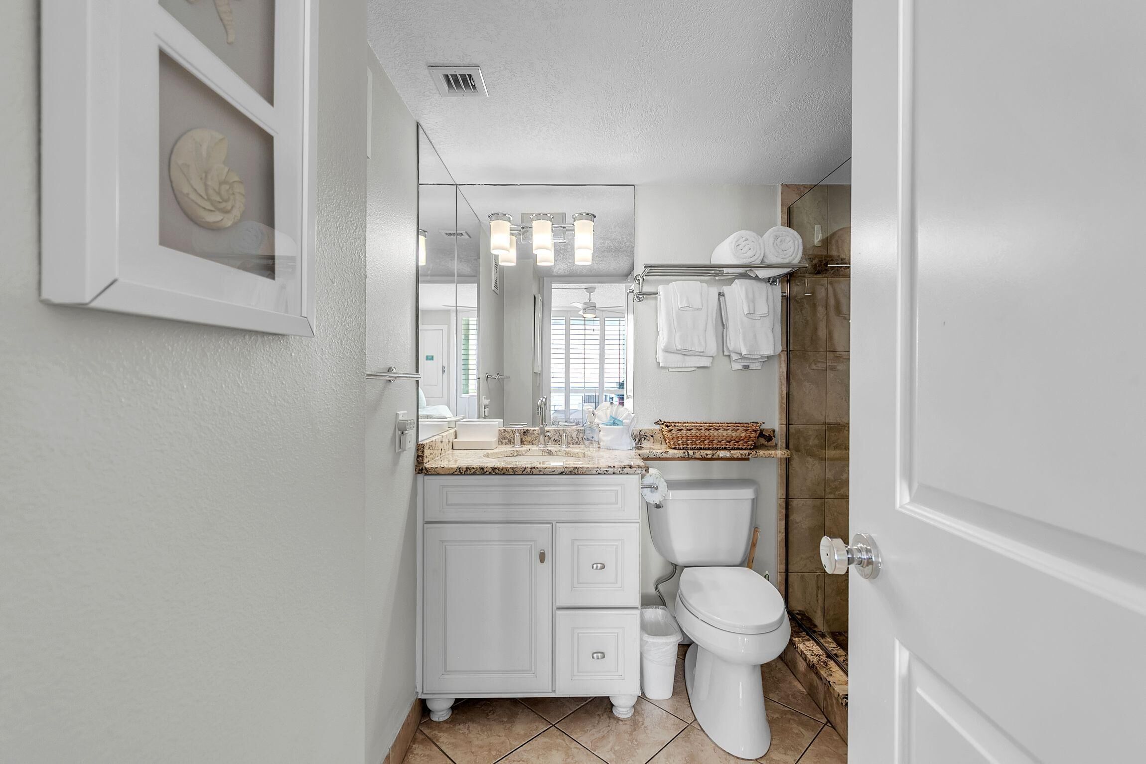 Une salle de bain avec un meuble-lavabo blanc, des toilettes, un miroir et un porte-serviettes.