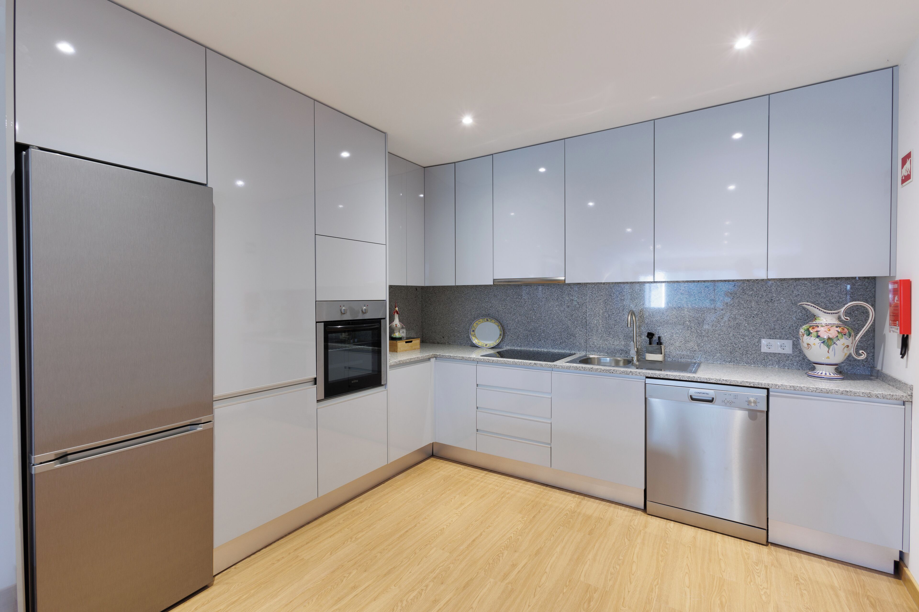 A modern kitchen with stainless steel appliances, grey cabinets, and a granite countertop.