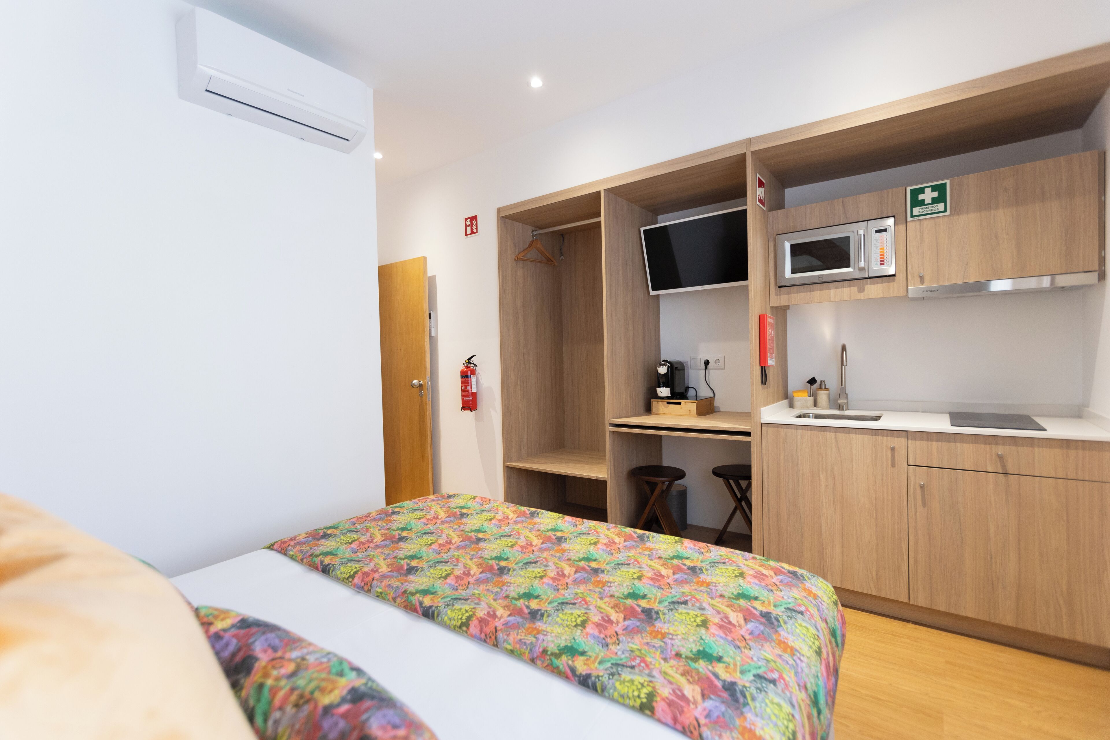 Habitación de hotel con cama, escritorio, microondas y una pequeña kitchenette.
