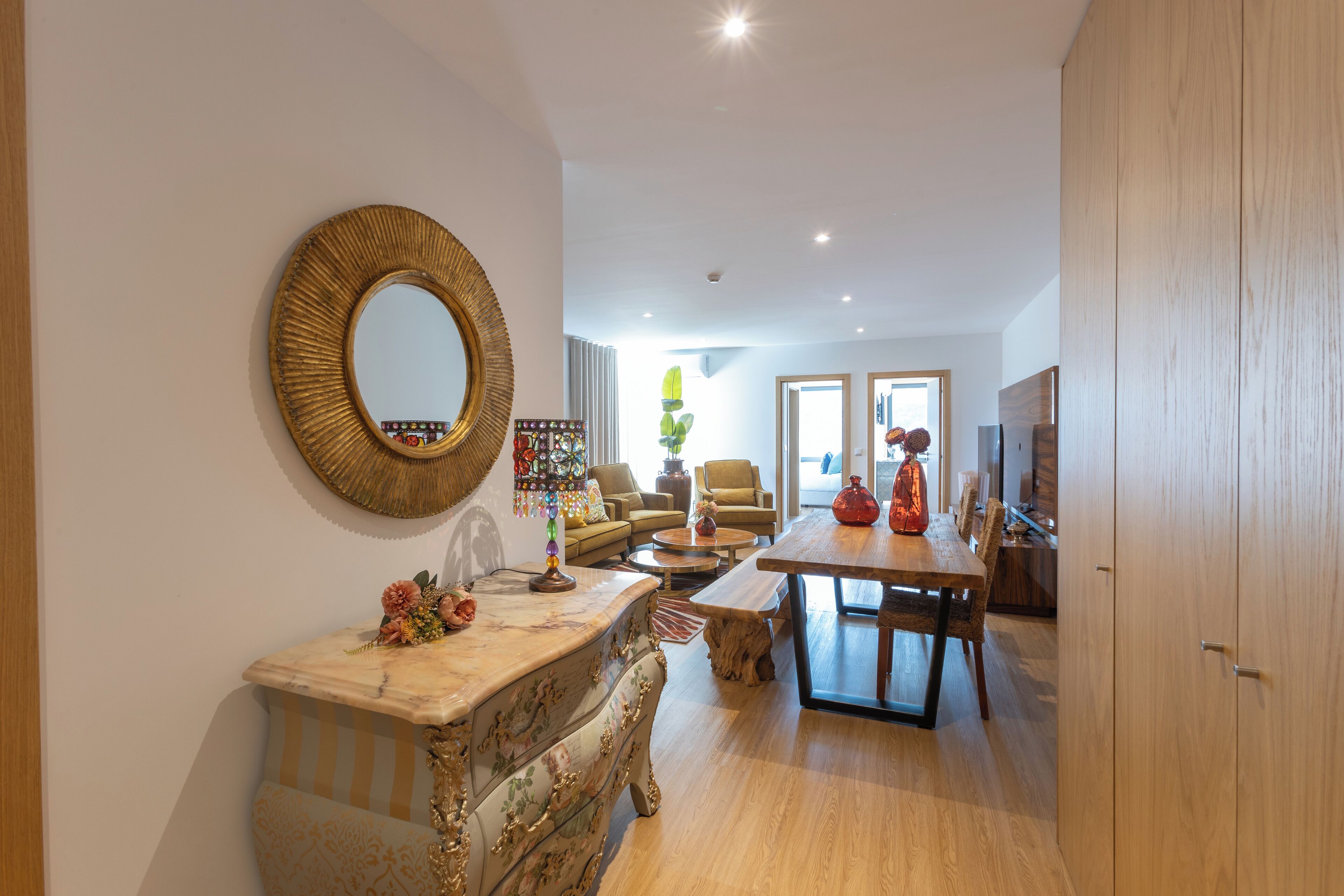 Een moderne woonkamer met een ronde spiegel, een eettafel en een bank.