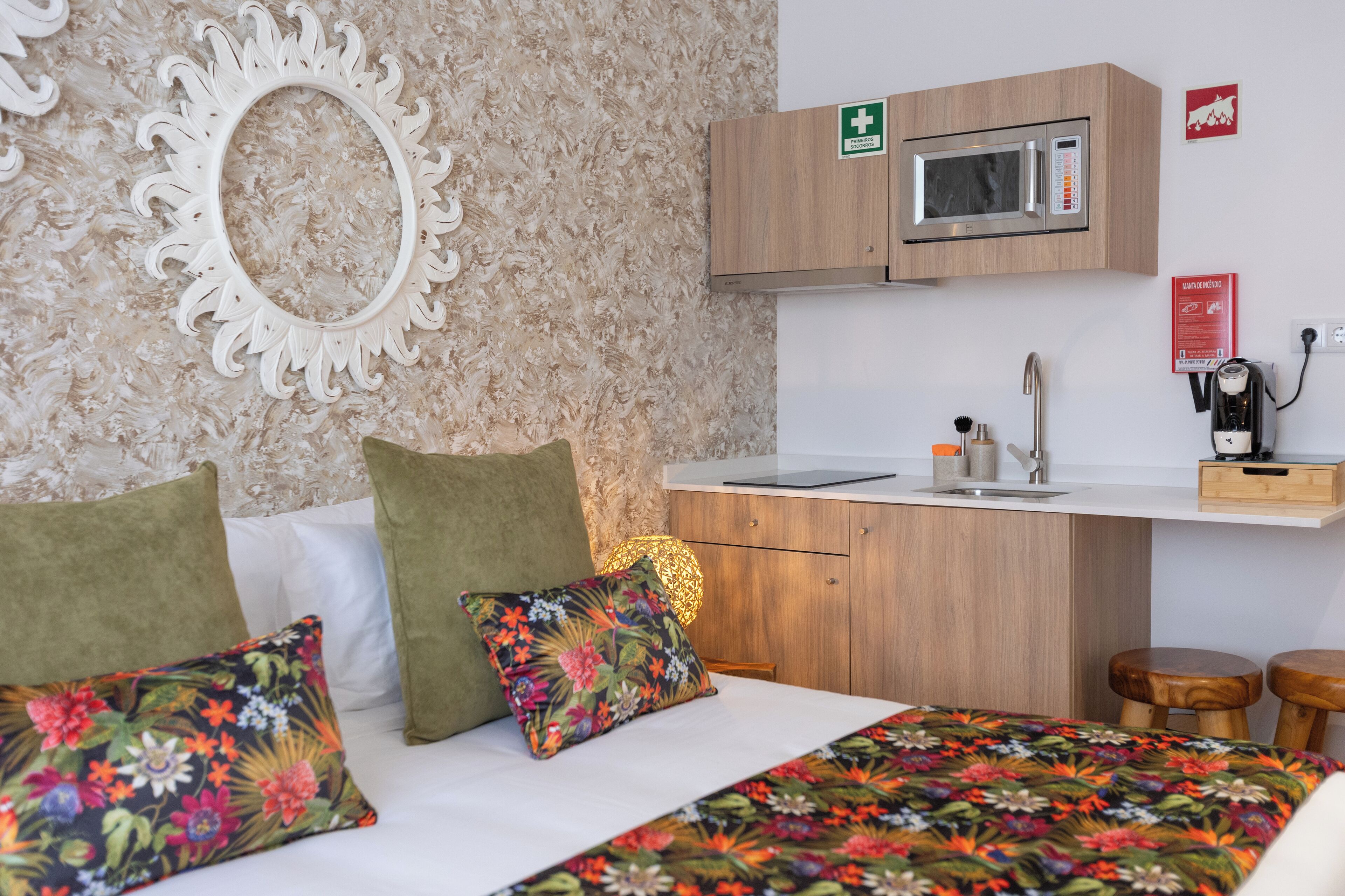 Una habitación con una cama, una pequeña kitchenette y un espejo en la pared.