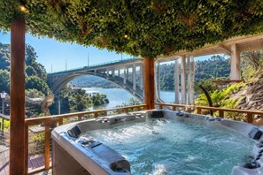 Un jacuzzi con vistas a un puente sobre un río, rodeado de vegetación.