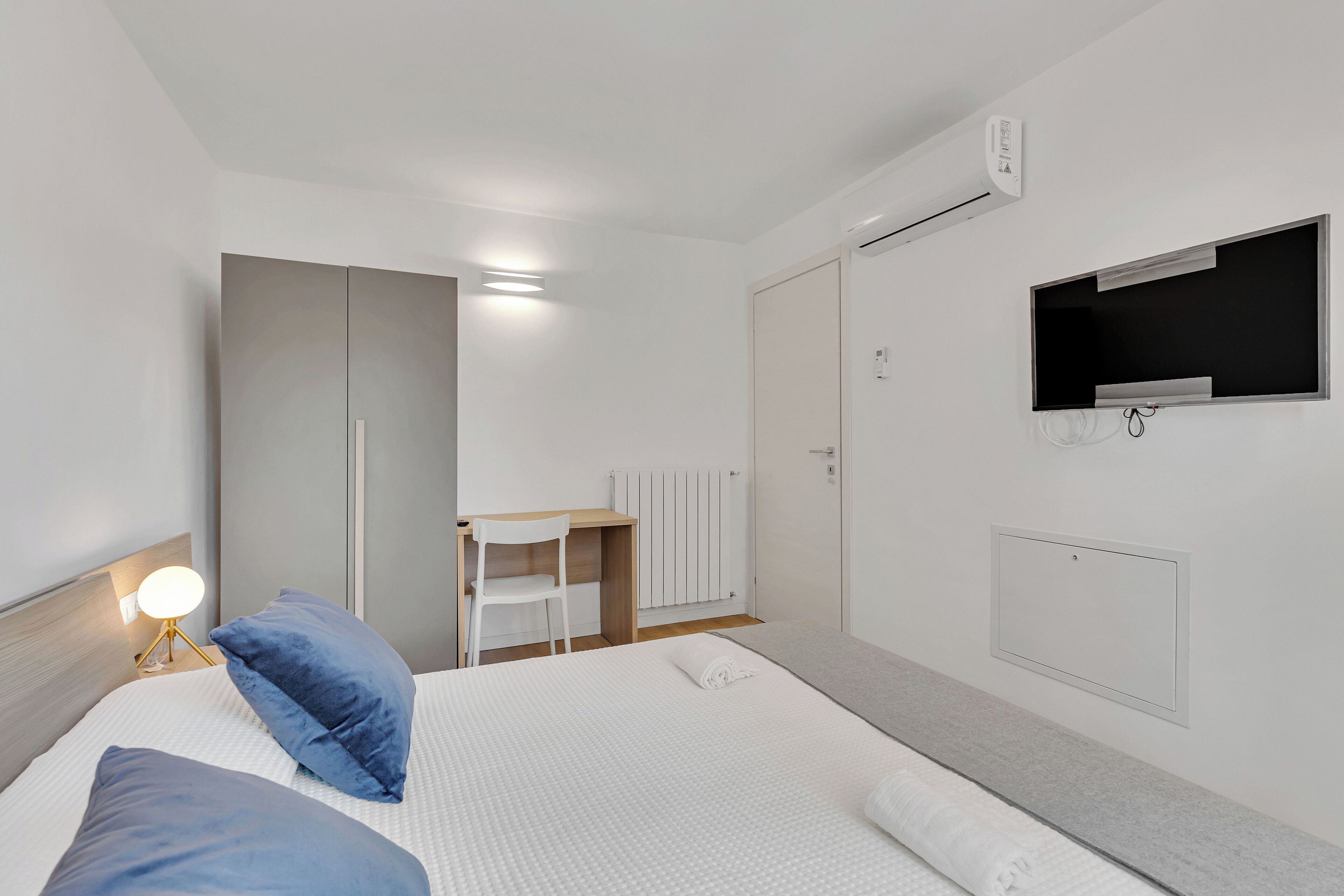 Una habitación de hotel moderna con una cama, un escritorio, una silla y un televisor.