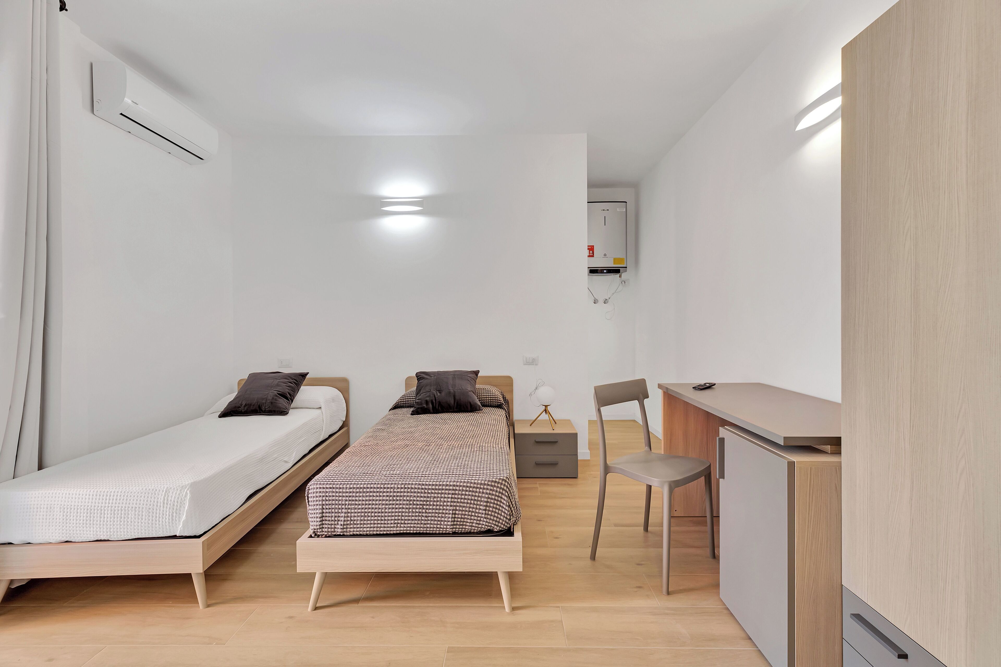 A small, modern bedroom with a single bed, a desk, and a chair.