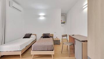 A small, modern bedroom with a single bed, a desk, and a chair.