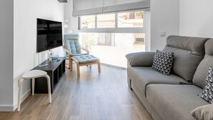 Una sala de estar moderna con un sofá gris, un sillón azul y un televisor montado en la pared.