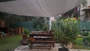 A patio area with a table and chairs, surrounded by potted plants and a stone pathway.