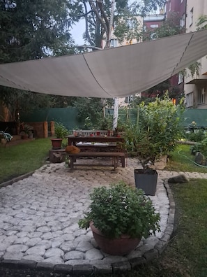A patio area with a table and chairs, surrounded by potted plants and a stone pathway.